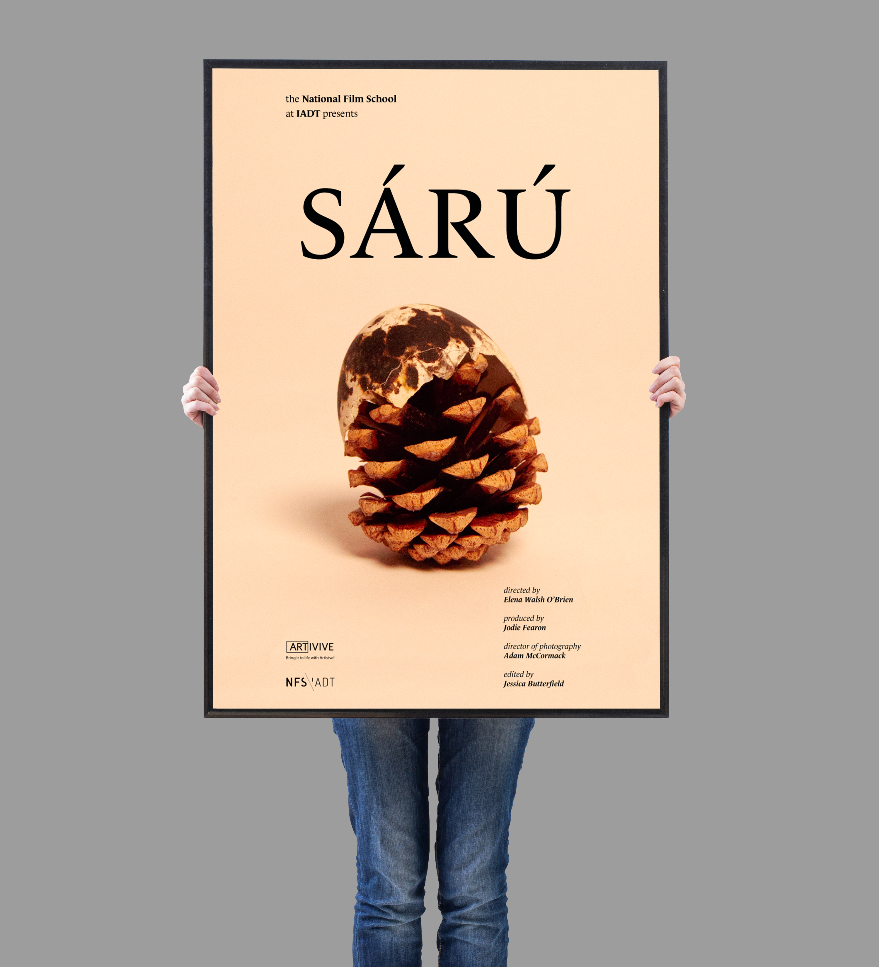 person holding a mockup image of the main Sárú poster featuring a pinecone topped with half an egg shell